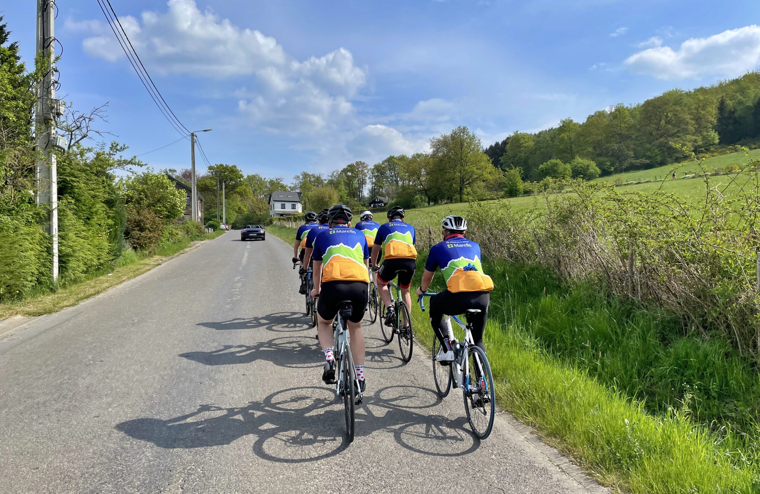 Eine Gruppe Radfahrer von Oro und Marello auf einer Straße bergauf